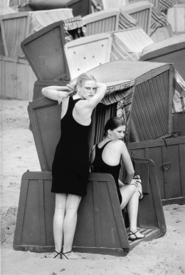 Sibylle Bergemann DDR Fotografie Marisa und Liane auf Rügen 1981, schwarz-weiß Fotografie von zwei jungen Frauen. Eine grimmig schauend an einen Strandkorb gelehnt und die andere sitzend