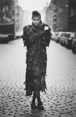 Sibylle Bergemann DDR Fotografie von Allerleirauh Heike in Berlin 1988, schwarz-weiß Fotografie von einer jungen Frau in einem großen Kostümmantel auf der Straße