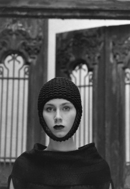 Sibylle Bergemann Modefotografie für Claudia Skoda Lily von Wild in Berlin 2009, schwarz-weiß Fotografie von einer Frau mit Strickmütze, die nur das Gesicht freilässt. Sie steht vor einer Tür mit gitterhaften Ornamenten